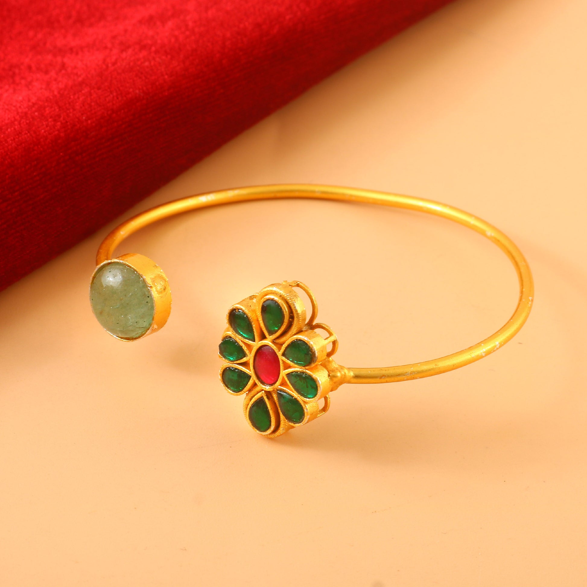 Gold Kundan Bangle Adorned with Green and Red Stones in Ornate Traditional Pattern